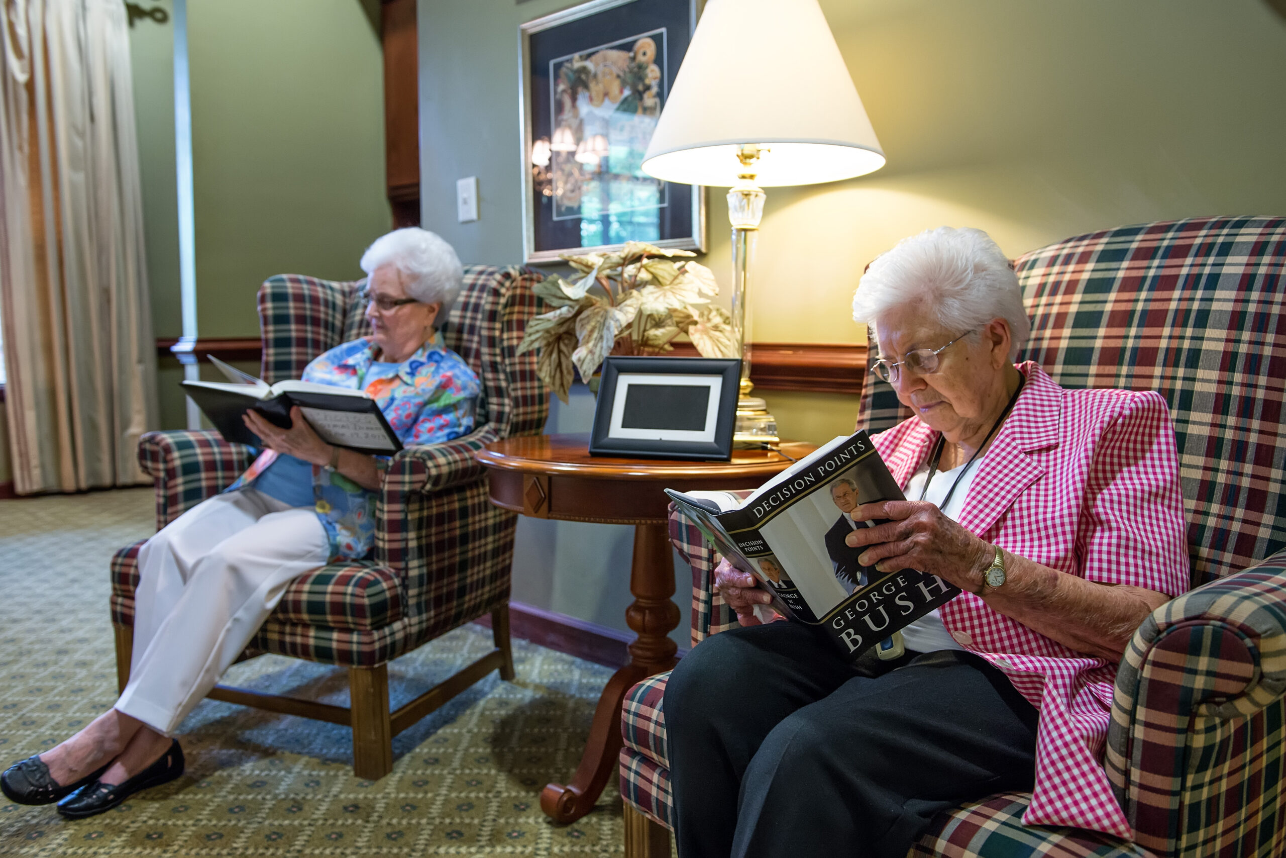 Two residents relaxing and reading in comfortable chairs